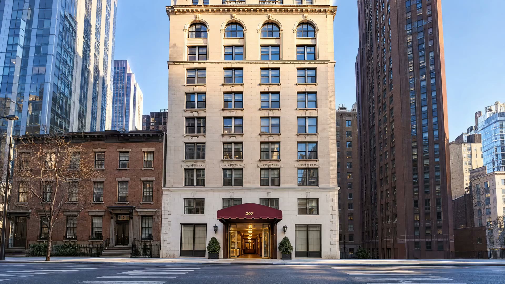 267 Fifth Avenue from across the avenue: a limestone facade with an oxblood awning over the entrance